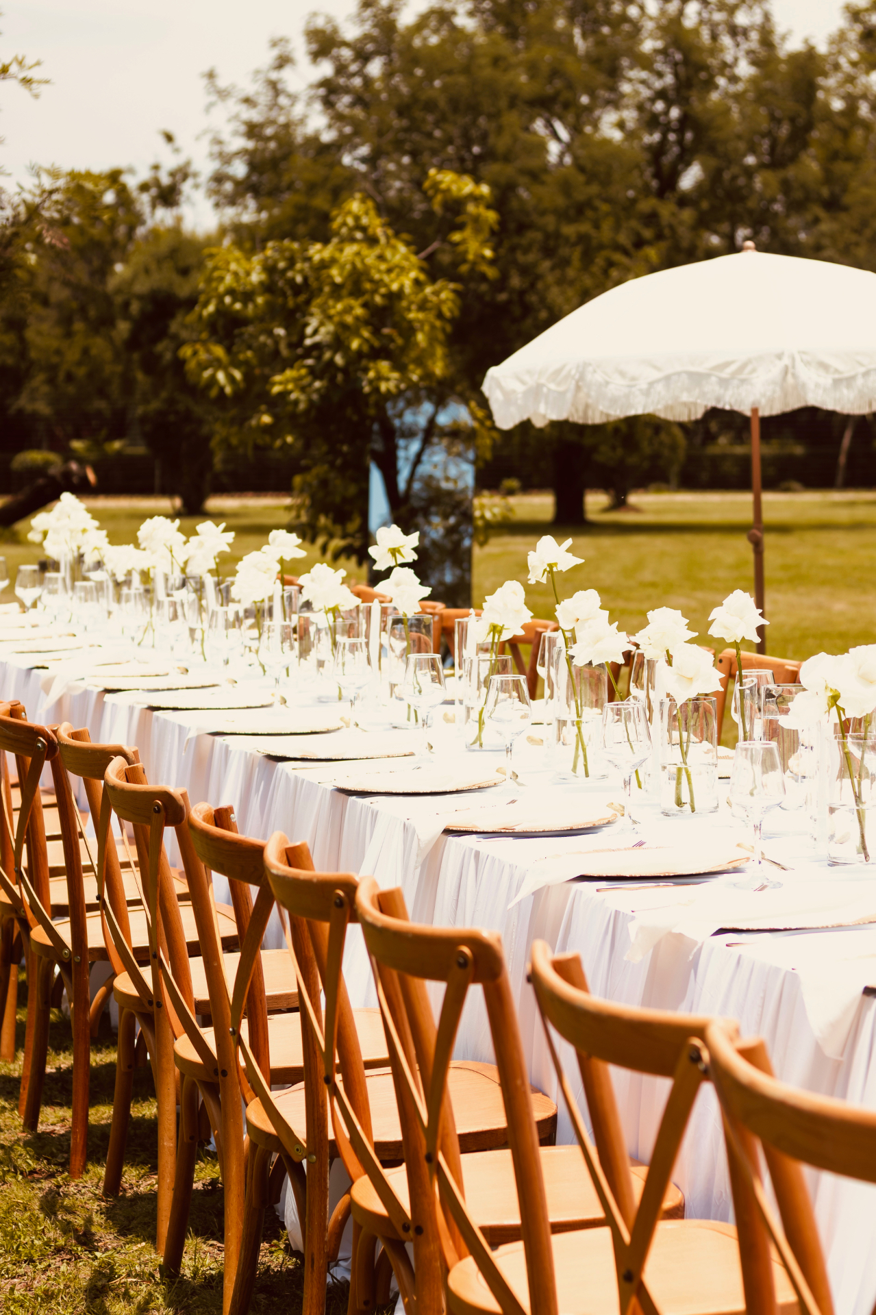Long white tablescape with white roses and crossback chairs