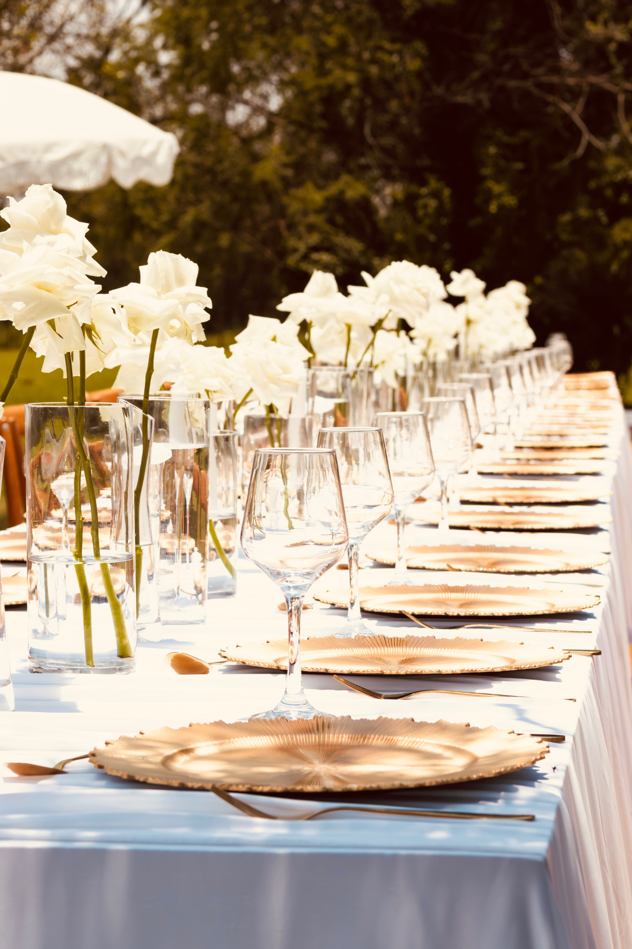 Gold charger plates and crystal glassware on a white tablescape