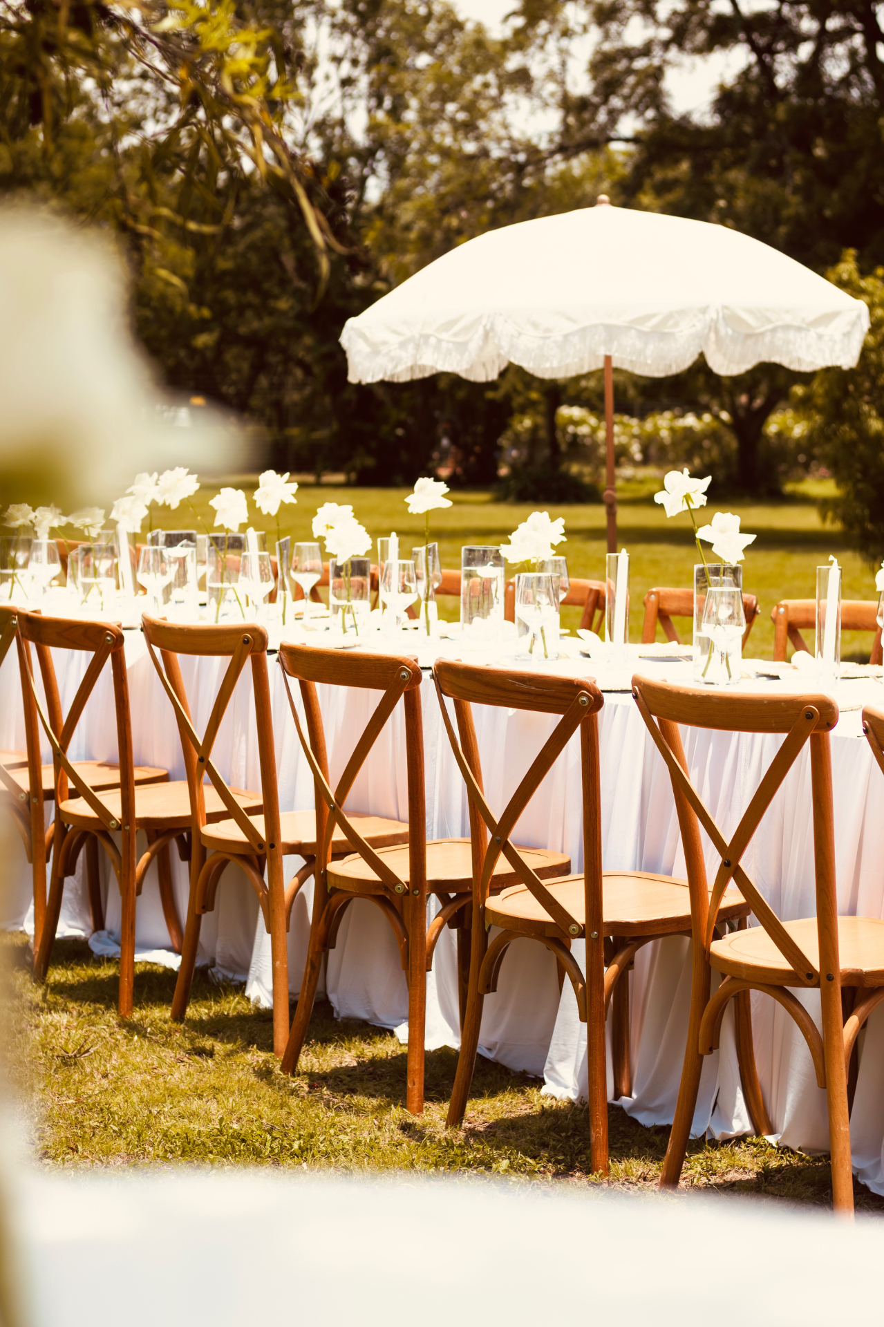 Round garden tablescape under a fringed umbrella