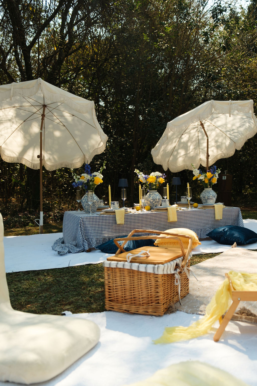 Long gingham picnic table set under cream fringed umbrellas